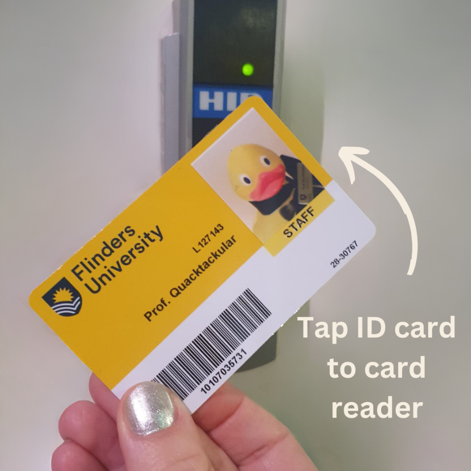 Flinders University ID card being held up against a small black rectangular box mounted to a wall.